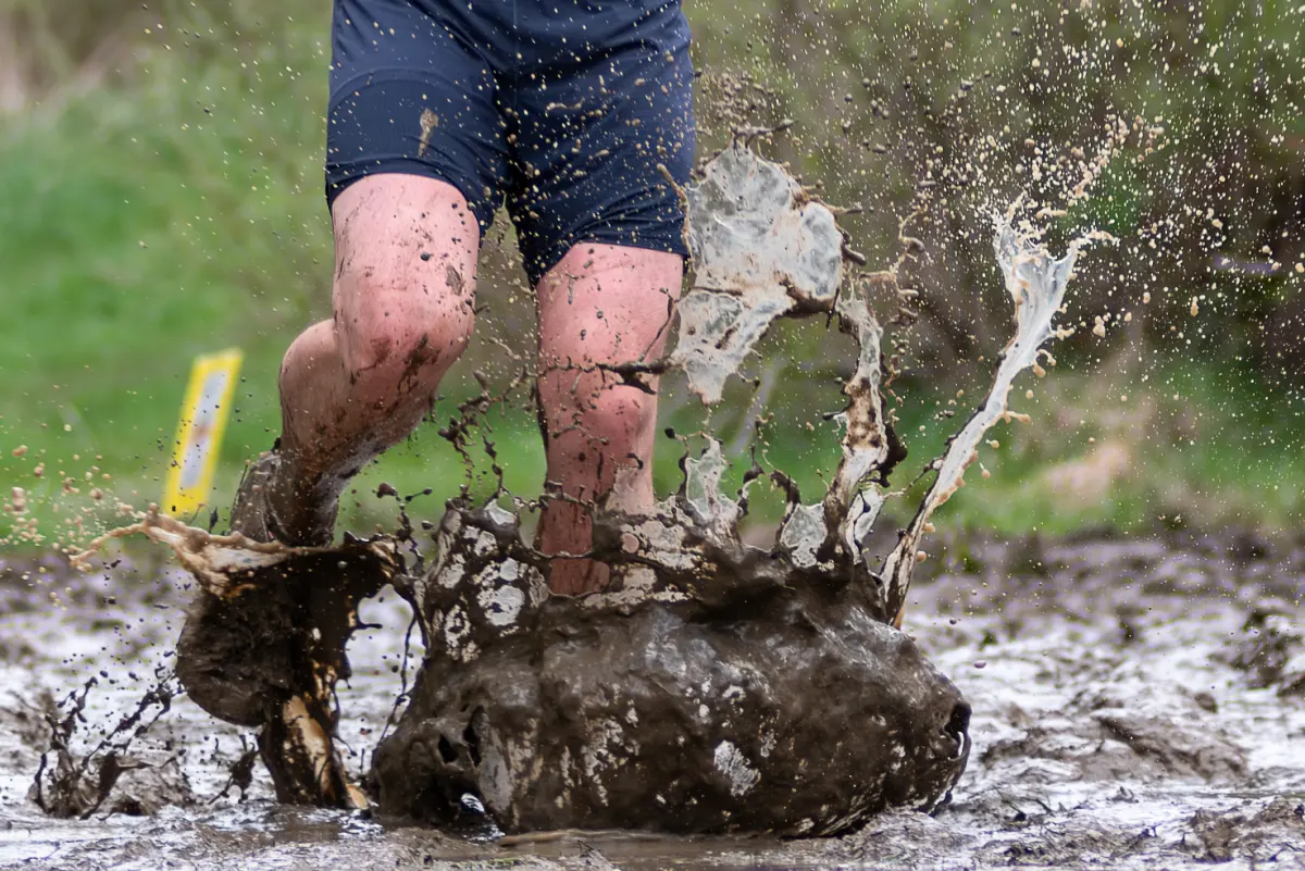 A runner splashing through deep mud at the Dirty Kiln Trail Races